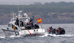 Spanish Civil Guards try to stop migrants before disembarking from a dinghy at "Del Canuelo" beach after they crossed the Strait of Gibraltar sailing from the coast of Morocco, in Tarifa